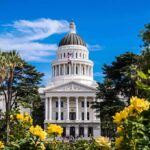 California’s Top State Paycheck Comes With A Twist Capitol building with white dome framed by trees and yellow flowers