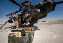 attack helicopter on tarmac with crew and ammunition crates