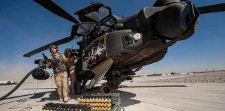 attack helicopter on tarmac with crew and ammunition crates