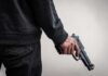 person holding a handgun at their side