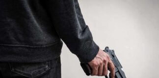 person holding a handgun at their side