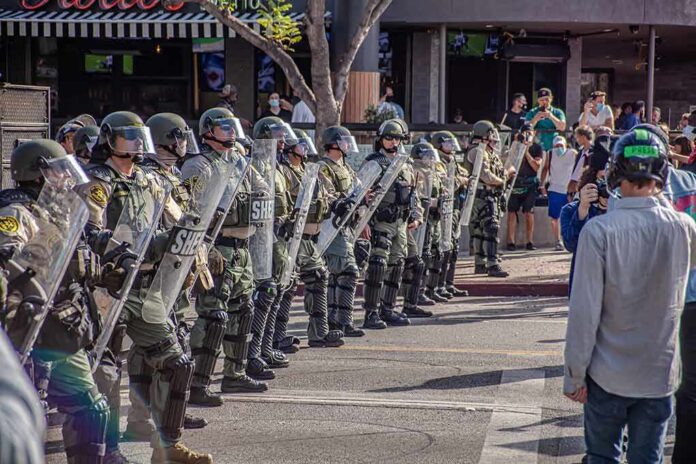 shutterstock_1756892879 Riot police in helmets and shields form a line on a city street
