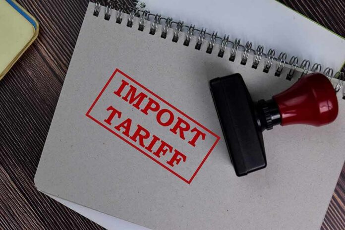shutterstock_1773748721 Notebook with import tariff stamp and red-handled rubber stamp