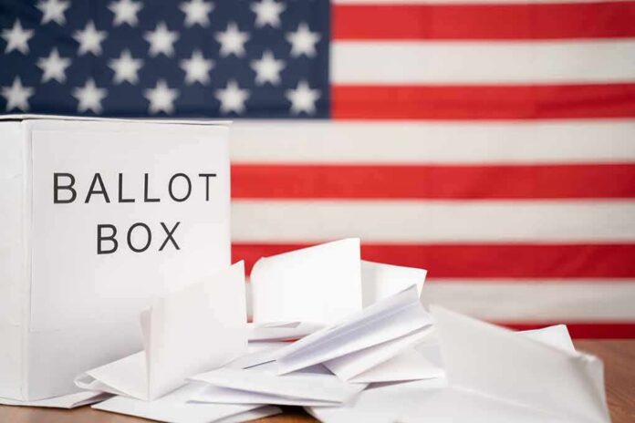 shutterstock_1818888026 Ballot box with papers in front of an American flag