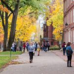 Controversial Voice Axed — Process Blamed Students walking through a leafy campus path in autumn