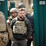 man in tactical vest walking with soldiers
