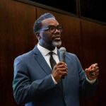 Parks, Schools Off-Limits—Arrests Halted Man in a suit speaking into a microphone