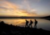 Eruption Chaos: Warnings Ignored, Rules Tighten hikers silhouetted by a lake at sunset