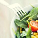 Produce Parasite Wrecks Career Momentum Salad with spinach, cherry tomatoes, corn, and feta in a bowl