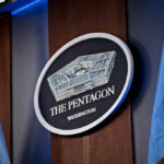 War Costs Are Quietly Rewriting The Pentagon Budget The Pentagon emblem between two flags.