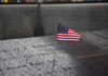 American flag on a rainy memorial nameplate.