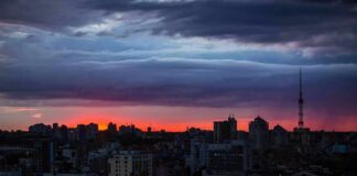 city skyline at dusk with dramatic clouds and orange horizon