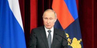 Vladimir Putin speaking at a podium with microphones