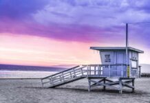 Lifeguard tower on a sandy beach at sunset with colorful sky