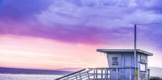 Lifeguard tower on a sandy beach at sunset with colorful sky