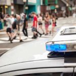 police car roof light bar with blue lights near a busy crosswalk