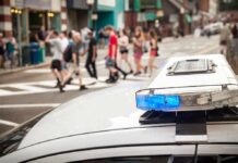 An After-Hours Fight Ended With Three Dead police car roof light bar with blue lights near a busy crosswalk