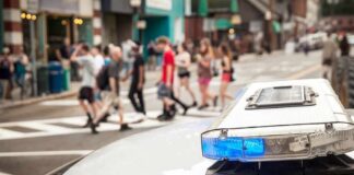 police car roof light bar with blue lights near a busy crosswalk