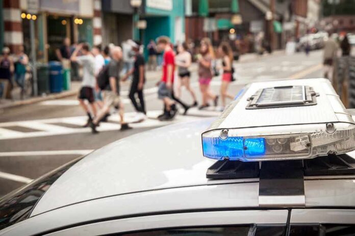 shutterstock_1107583991 police car roof light bar with blue lights near a busy crosswalk