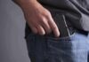 Hand placing a handgun into a jeans pocket