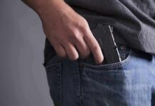 Lifetime Gun Ban Faces Meltdown Hand placing a handgun into a jeans pocket