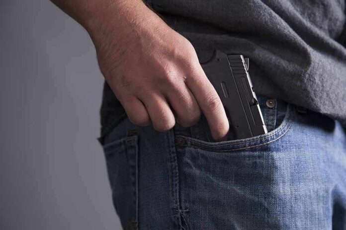 shutterstock_113470597 Hand placing a handgun into a jeans pocket