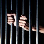 hands gripping prison bars