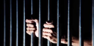 hands gripping prison bars
