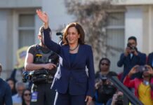 Detroit Dodge: Harris Keeps 2028 Open woman in navy suit waving at an outdoor event