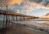 Boardwalk Shredded – Worse Hits Next Week Wooden pier stretching over ocean waves at sunset