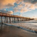 Boardwalk Shredded – Worse Hits Next Week Wooden pier stretching over ocean waves at sunset