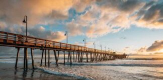 Wooden pier stretching over ocean waves at sunset