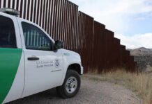 Stuck At Sunset—Border Patrol Rolls In Border patrol SUV parked beside tall steel border fence