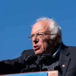 elderly man speaking at outdoor podium