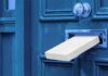 White package halfway through a blue door mail slot