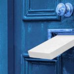 White package halfway through a blue door mail slot