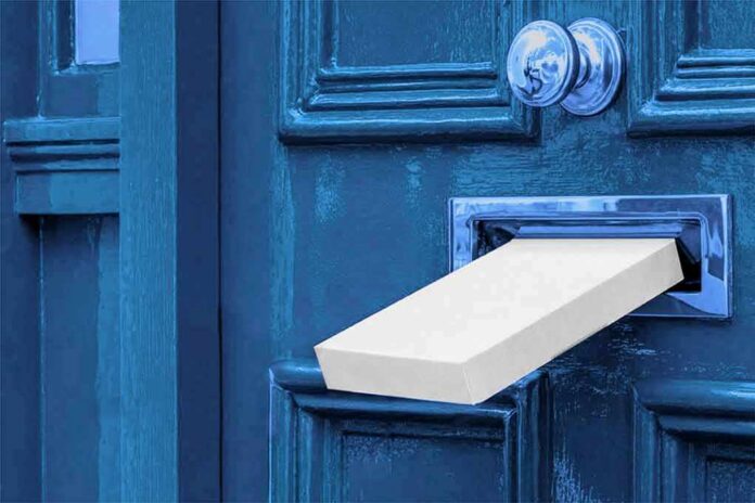 White package halfway through a blue door mail slot