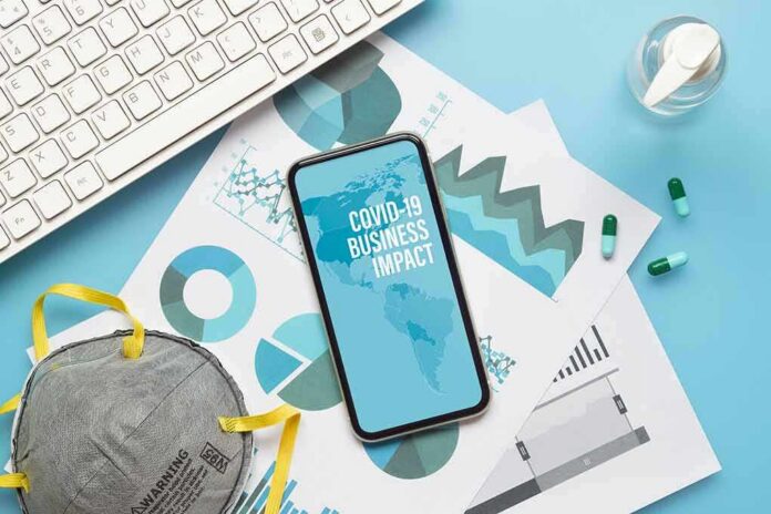 Smartphone on business charts with mask, keyboard, pills, and hand sanitizer