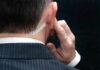 security agent with earpiece touching ear