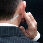 security agent with earpiece touching ear