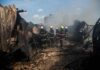 Firefighters amid twisted metal and smoke at a disaster site