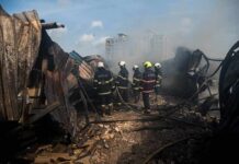 Firefighters amid twisted metal and smoke at a disaster site