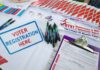 Voter registration table with forms, pens, and informational materials