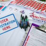 Cash-for-All Promise Sets Congress on Edge Voter registration table with forms, pens, and informational materials