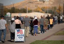 Michigan Poll Flashpoint – Bias Debate Explodes voters standing in a long line outside a polling place