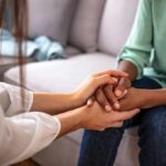 Two people holding hands on a couch