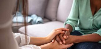 Two people holding hands on a couch