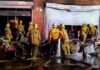 Encampment Infernos Overwhelm LA Firefighters work outside a damaged warehouse with debris and hoses