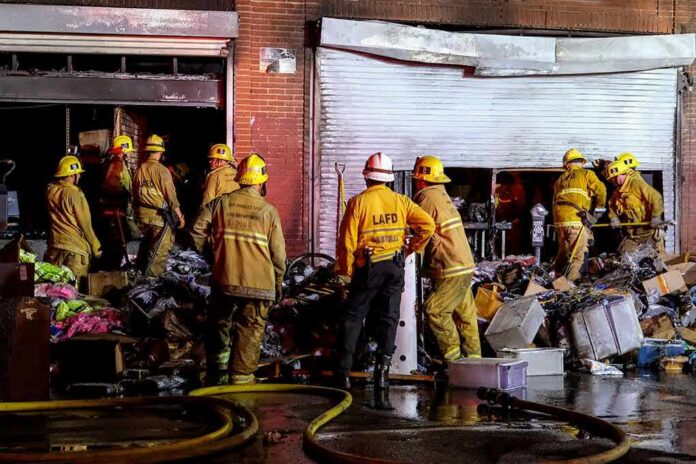 shutterstock_1988032958 Firefighters work outside a damaged warehouse with debris and hoses