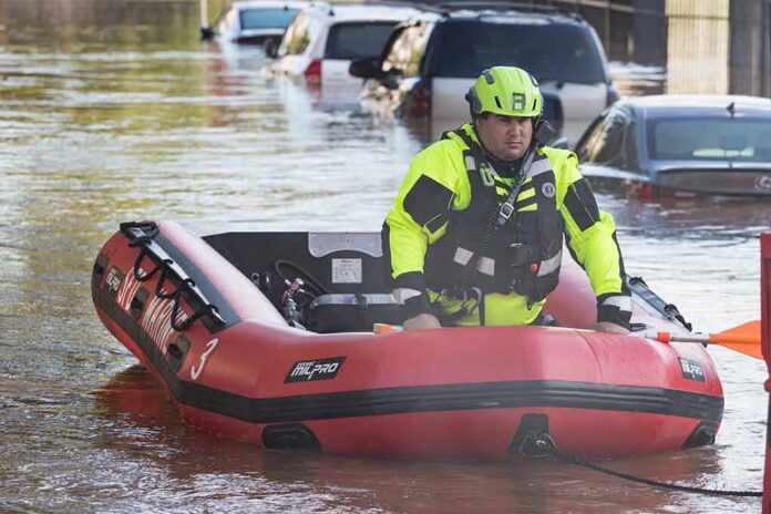 shutterstock_2035377782 Rescue worker in an inflatable boat during urban flooding
